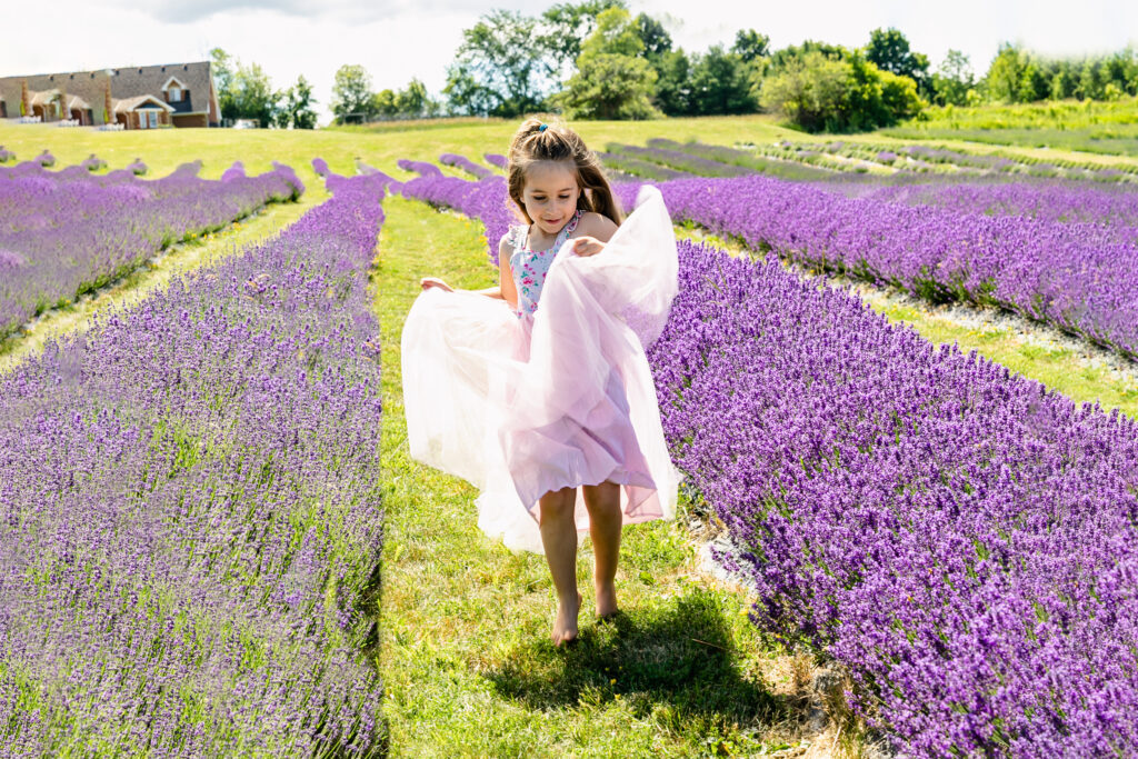 Young girl enjoying a playful photo session in lavender fields.