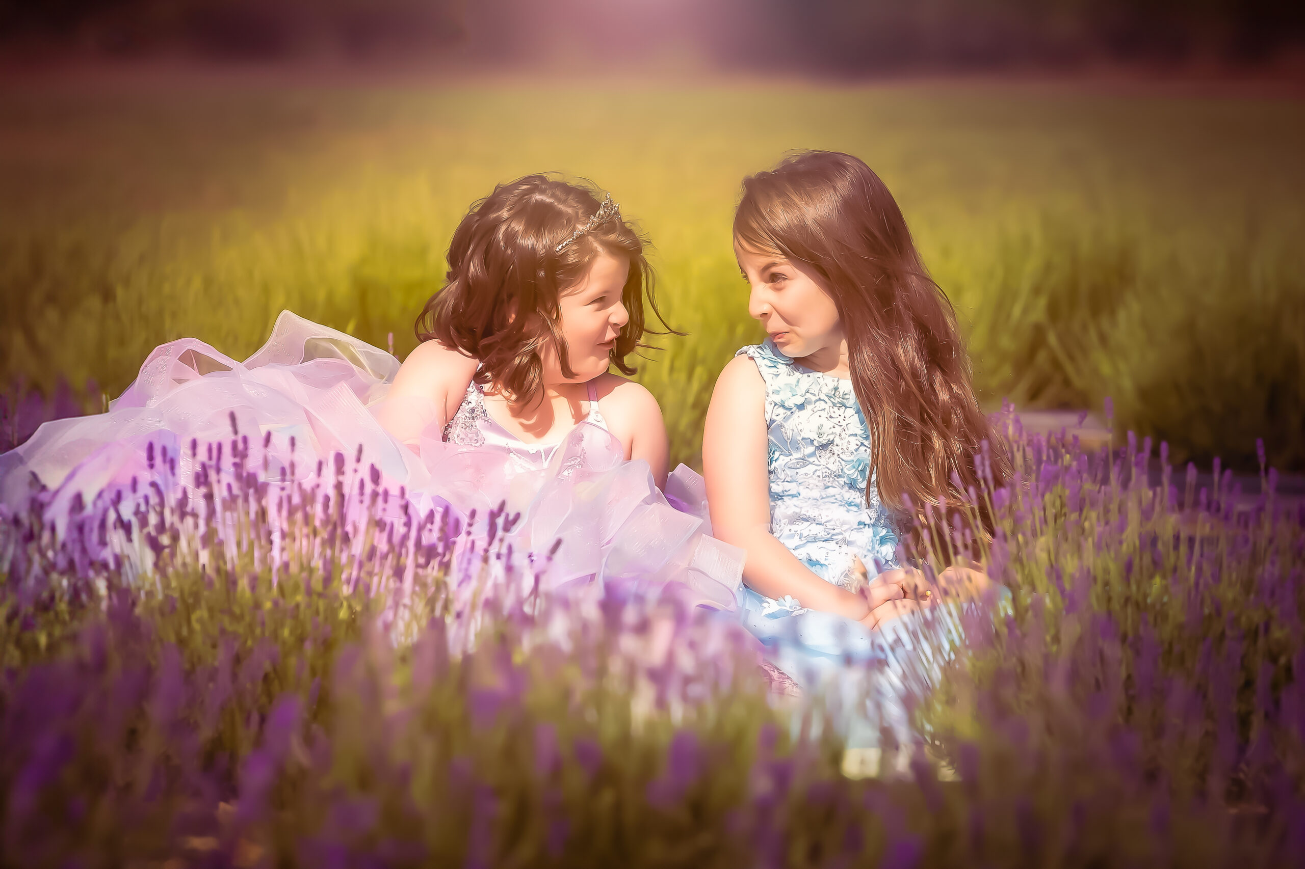 Two girls in princess gowns making funny faces in lavender fields.