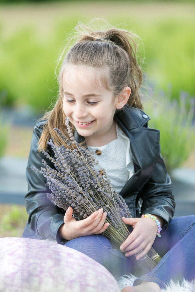 Young girl laughing with lavender bouquet during a photo session.